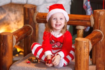 Święta, dziewczynka w czapce Mikołaja, koło kominka